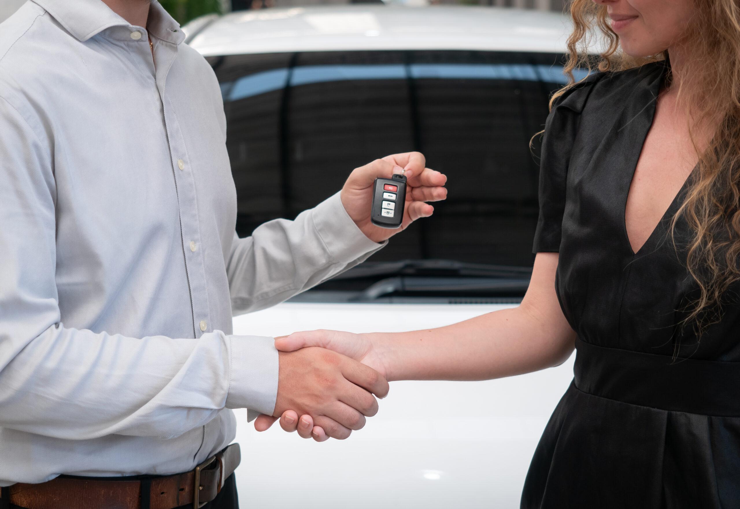 Mujer y hombre estrechando su mano y recibiendo llaves de auto