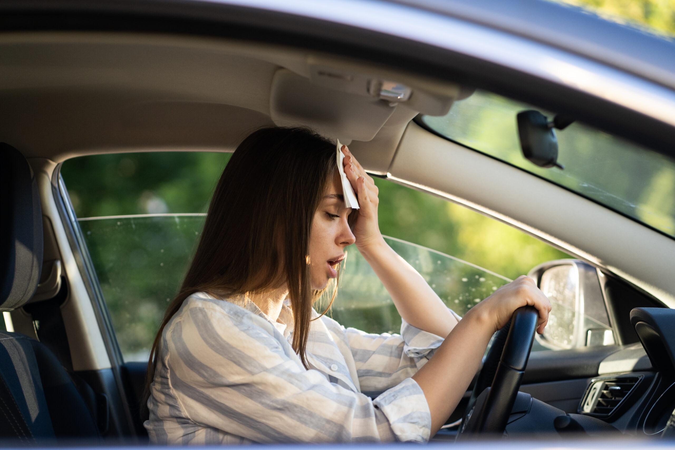 Mujer secandose el sudor en su auto por problemas con su AC
